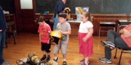 Oliver, Justin, and Olivia trying on fire equipment for size.