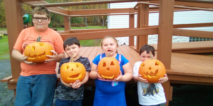 Reggie, Justin, Olivia, and Oliver holding their carved pumpkins.