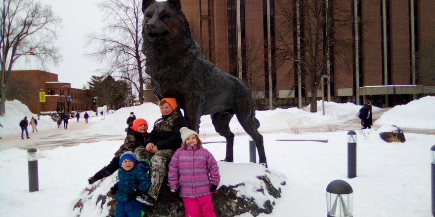 Oliver, Olivia, Justin, and Reggie gather in front of MTU Husky statue during snow sculptures 2022.