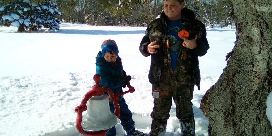 Oliver and Reggie ring the bell at Omer's Golf Course during snowshoeing trip.