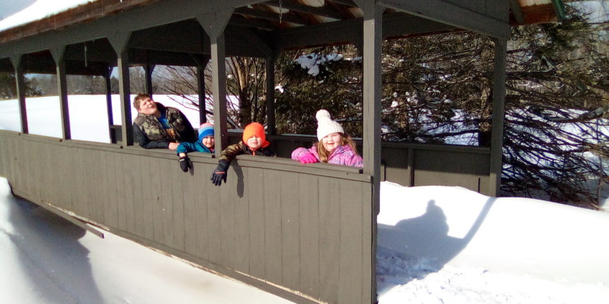 Reggie, Oliver, Justin, and Olivia posing for a picture in the covered bridge at Omer's Golf Course.