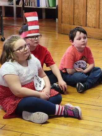 Olivia, Justin, and Oliver sitting quietly during book reading time.