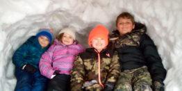 Oliver, Olivia, Justin, and Reggie sitting in the igloo.