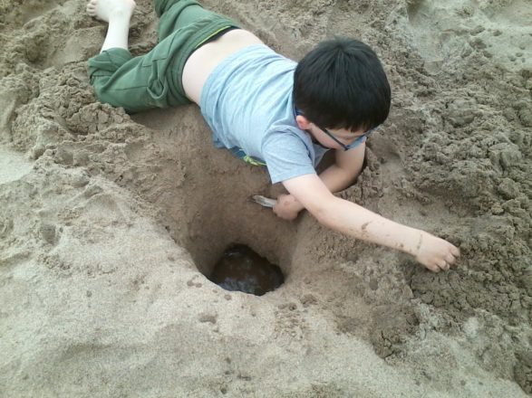 Oliver digging a hole at the beach.