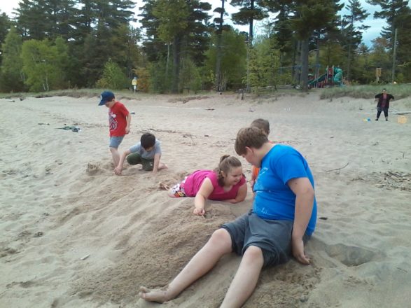 Reggie, Olivia, Justin, and Oliver at the beach in Ontonagon digging in the sand.