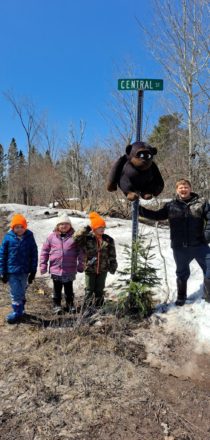 Oliver, Olivia, Justin, and Reggie standing at the road sign with the stuffed toy gorilla.