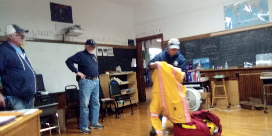 Twin Lakes Fire Dept. crew showing kids what is inside their fire suit equipment bag.