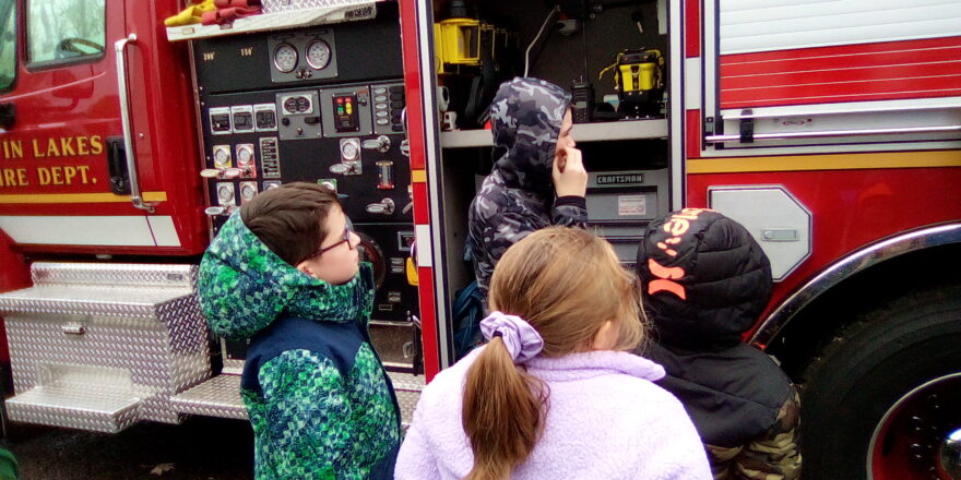 Avery, Olivia, Jacob, and Justin looking at fire truck tools.