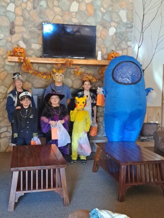 Ms. J. Reggie, Jacob, and Avery in his blue costume standing in front of the fireplace at Parkview, with Justin the ship captain, Olivia the witch, and Oliver the Minecraft character in yellow.