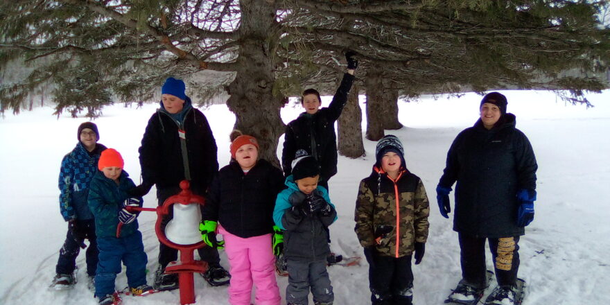 kids all ringing the red bell at the golf course during the snowshoe outing.