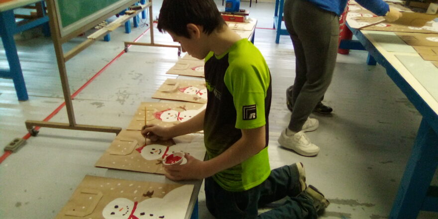 Jacob painting snowman on the bags for Little Brothers.