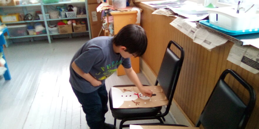 Justin is painting snowflake dots on the Little Brothers Christmas bags.