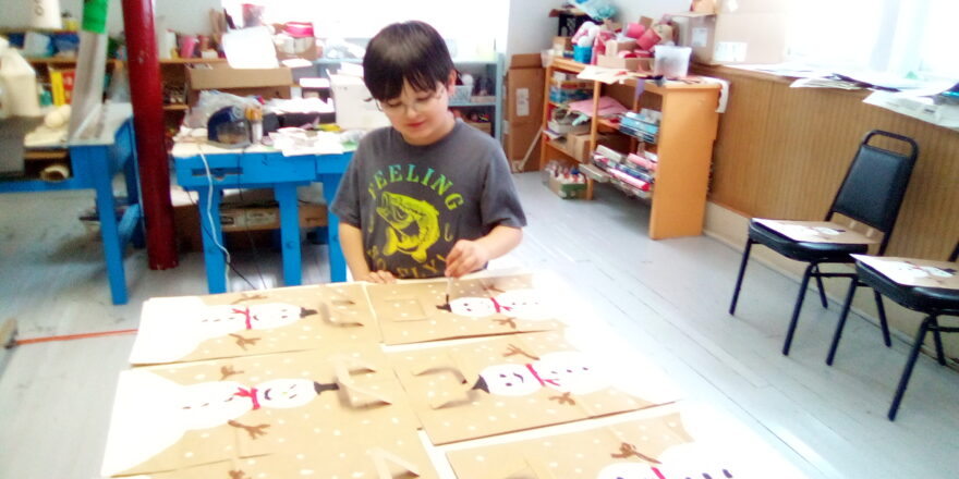 Justin is painting black top hats on snowmen for the Little Brothers Christmas bags.