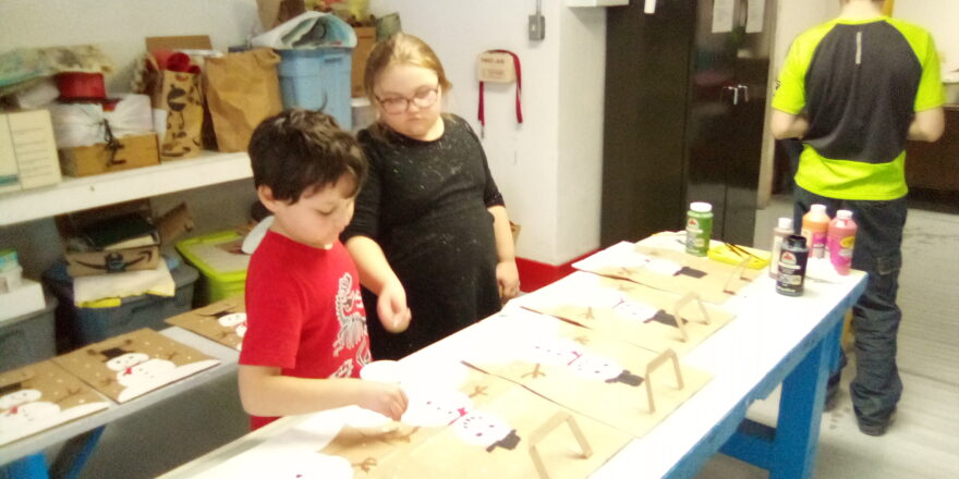 Oliver, Olivia, and Jacob painting snowmen on the Little Brothers Christmas bags.