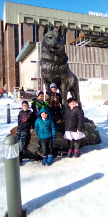 Kids hang out with the MTU husky statue in between looking at snow sculptures.