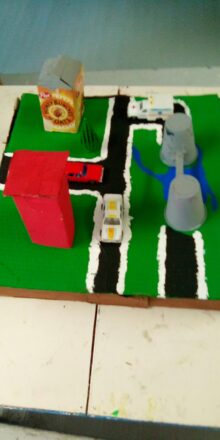 The earthquake model is now complete with big red building,, a Post cereal factory , some towers with a bridge and a roadway with cars on it;