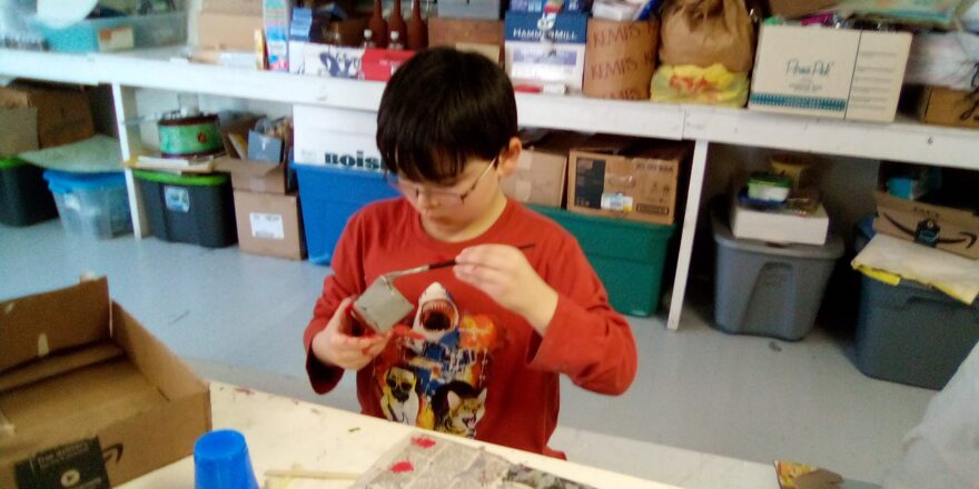 Justin is painting some grey color on one of his buildings for the earthquake model.