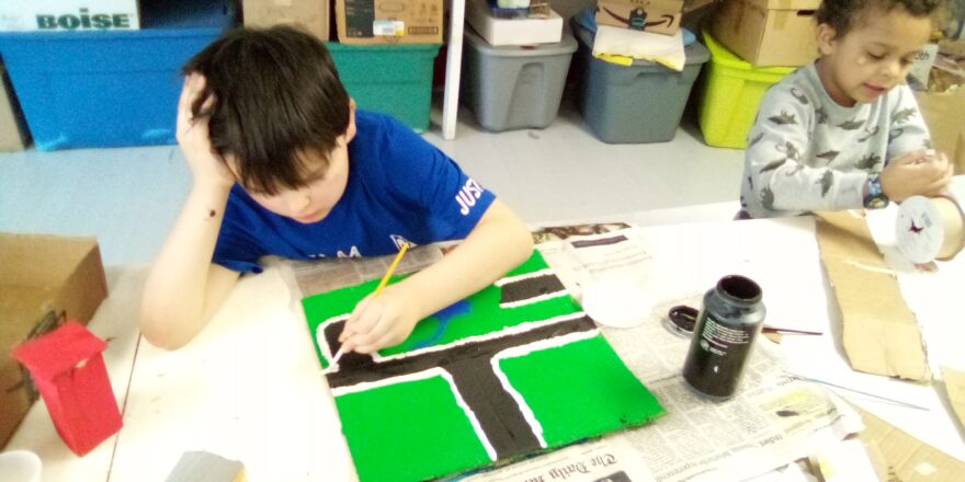 Justin is painting the outlines for the road in white for the earthquake model. 