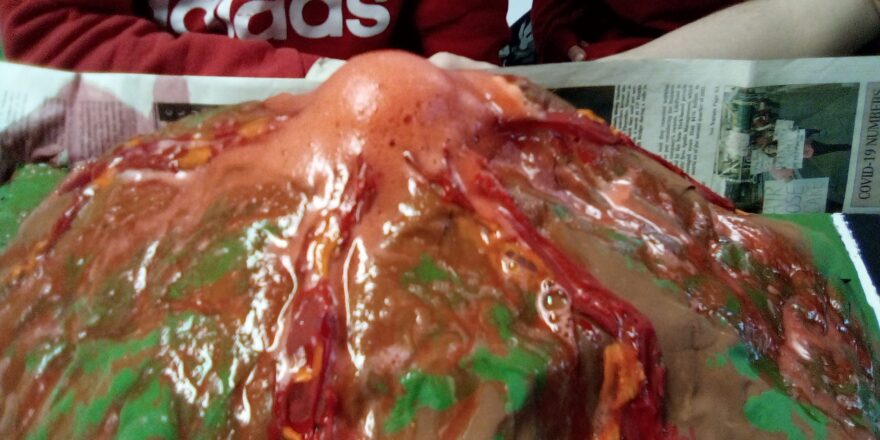 the lava is flowing out of the volcano and down the mountain. The lava was created with baking soda, dawn dish soap, red food color, and vinegar.