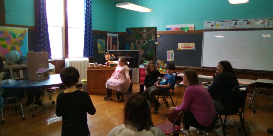 Kids sitting around the table during Easter Hunt games. Watching kids put Easter bunny parts on face. 