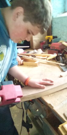 Reggie using the belt sander to smoothen out some serious rough edges of his dulcimer.