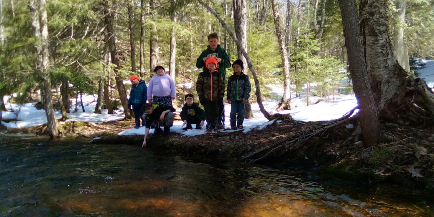 Elm River School kids standing by the rivers edge of the Wyandotte water falls in early spring 2023.