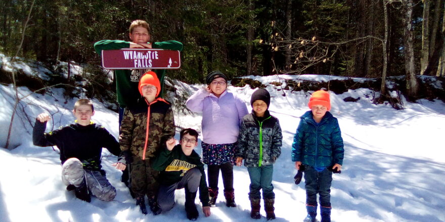 Elm River School kids on a field trip standing at the sign of the Wyandotte water falls. 
