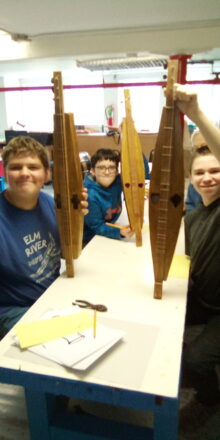 The three students showing off their newly built dulcimers.