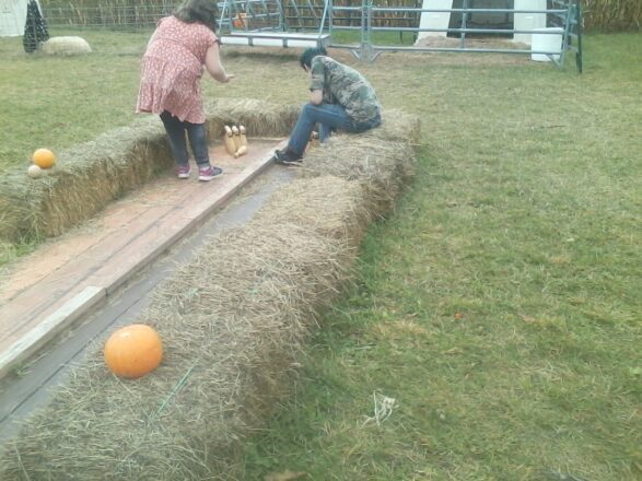 Kids playing with the pumpkin bowling lanes at the Palosaari Corn maze.
