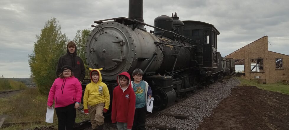 Students getting their picture taken in front of a steam train. 