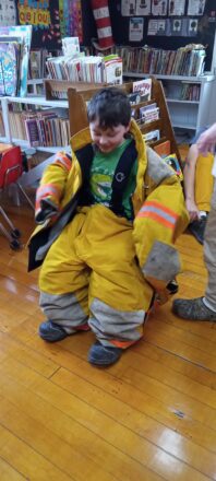 The little ones at the school get a chance to try on some of the fire suits that the crew wears to put out fires.