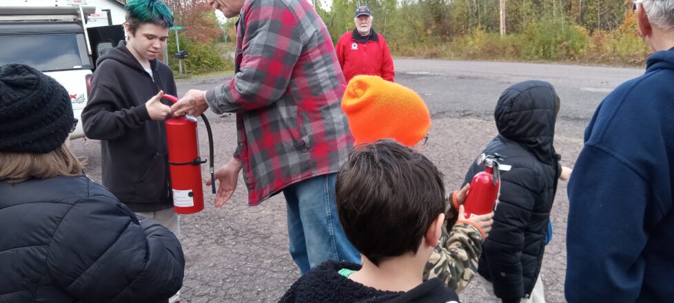 Fire Dept. showing how to hold and pull the pin out of a fire extinguisher.