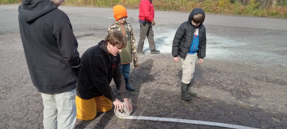 Teaching the bigger kids how to roll up a fire hose after all the water is drained out.