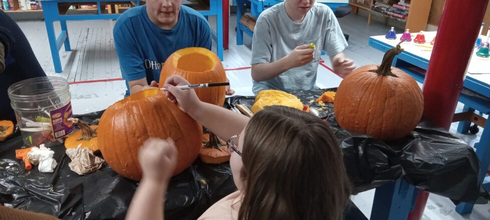 All the kids sitting at the art table carving, drawing, and digging out the guts on their pumpkins.