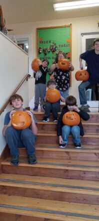 The carved pumpkins are being held by their creators on the steps of the school entrance before they take them home for the weekend of Holloween.