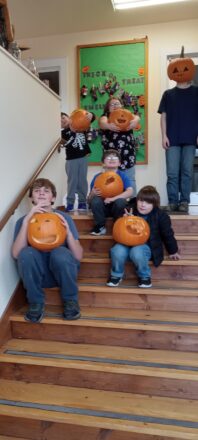 All the kids sitting on the entrance steps holding their pumpkins ready to take home.