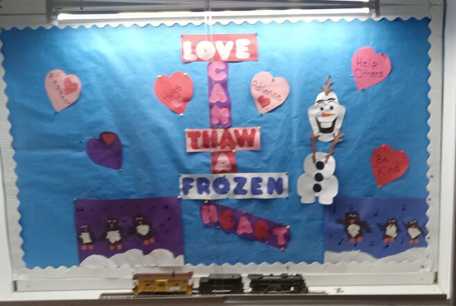 Bulletin Board decoration . Love can thaw a frozen heart. It has pink and purple hearts scattered around with positive messages written on them. There are also two art project pictures with penguins dancing that were made from cut up pieces of paper.