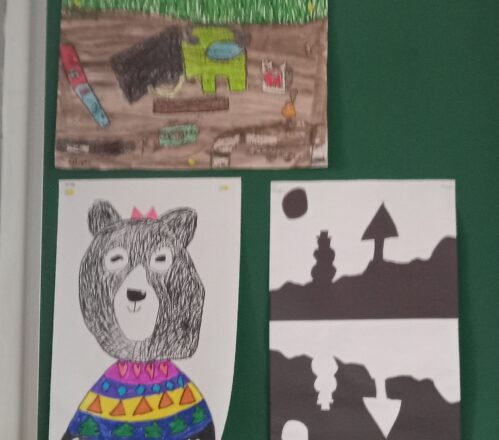 3 different art examples on the display board. The one on top shows items that you would dig up and find in the future if the kids buried them today. The one below is a drawing of a bear wearing a sweater and a bow on top of her head. The hair is done using black marker with short stroke line shading.