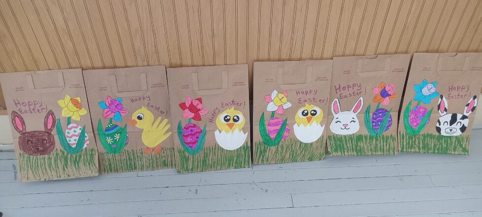 Easter bags decorated with little duck chicks walking in the grass next to a colorful egg and a flower. Other bags have a brown or white bunny head next to a flower and an Easter egg.